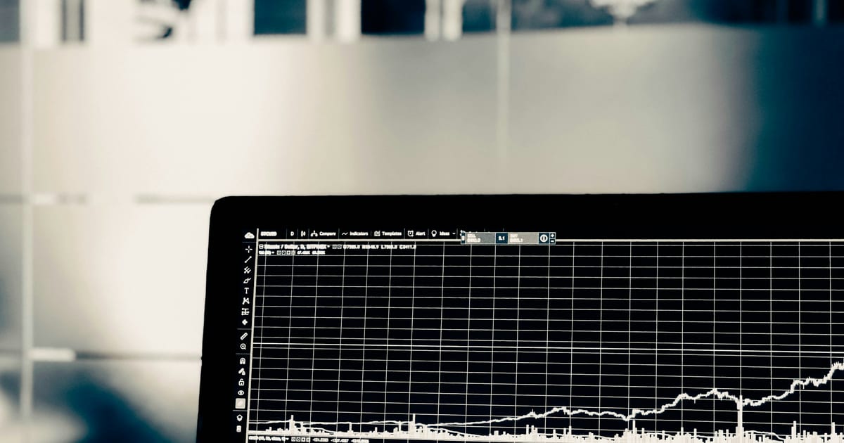 A dark laptop screen showing a faint white equity curve drawn over a fine grid