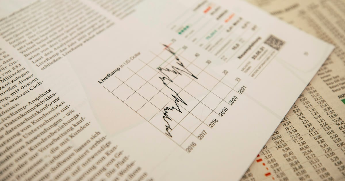 A newspaper business page showing a small line chart beside columns of figures
